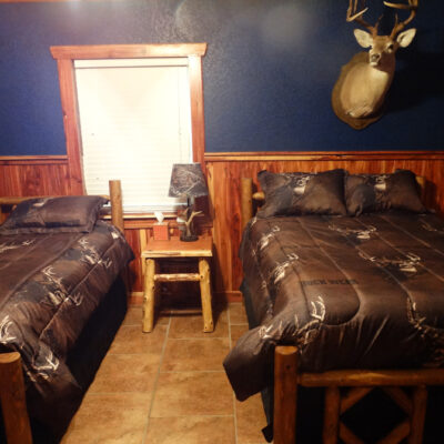One twin bed and one full bed with half blue walls and half wood slats on walls